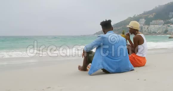 非洲裔美国夫妇在沙滩上喝菠萝汁4k的后视图视频的预览图