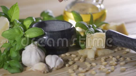 帕尔马干酪松子海盐和大蒜用于制作木桌上的罗勒有害生物酱视频的预览图