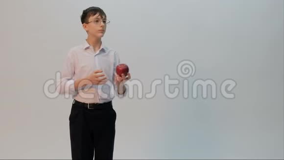 一个戴眼镜的年轻人提出要吃一个红苹果一个穿着白色衬衫的滑稽学生脸上流露出悲伤的情绪视频的预览图