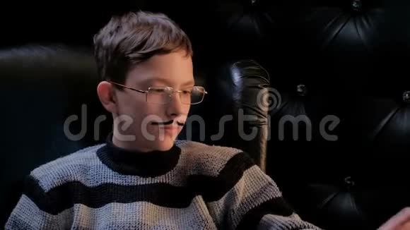 一个戴眼镜留着八字胡的年轻人坐在黑色扶手椅上拿起一个红苹果一个男人脸上悲伤的表情视频的预览图