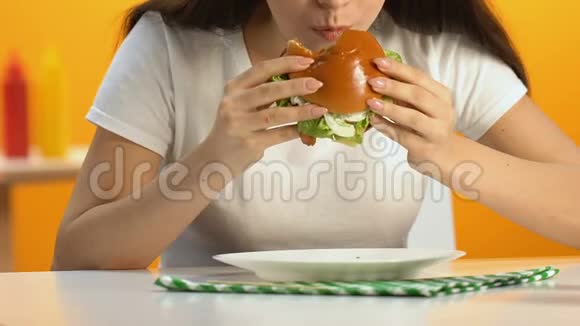 女性在快餐店吃高脂肪的汉堡食欲旺盛饮食肥胖视频的预览图
