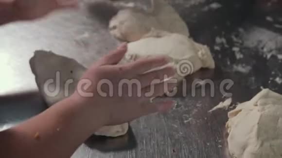 女人的手在厨房里用面团在不锈钢工作台上工作视频的预览图