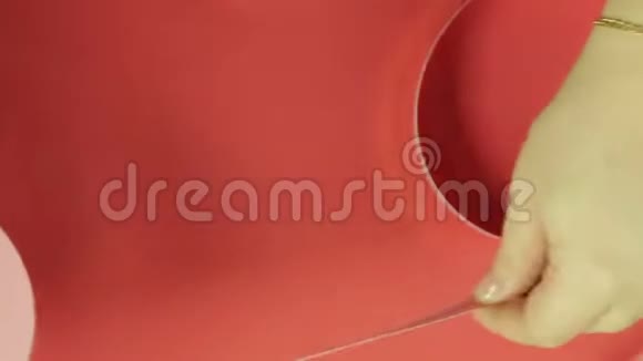 女人手量一条粉红色的丝带做礼物蝴蝶结红色背景视频的预览图