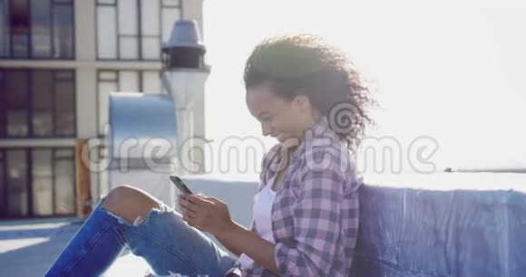 城市屋顶上使用智能手机的时尚年轻女性视频的预览图