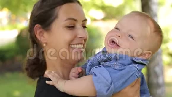 一位母亲在一个夏天的公园里拥抱她五个月大的儿子视频的预览图