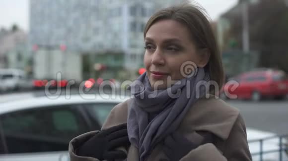 秋天冻僵的女人裹着外套等待公共交通的到来视频的预览图