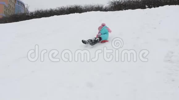 一个冬天的孩子滚下山小女孩在冰上慢动作视频的预览图