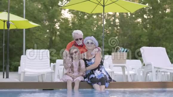 肖像成熟的夫妇拥抱小孙女在池边祖母祖父和孙子视频的预览图