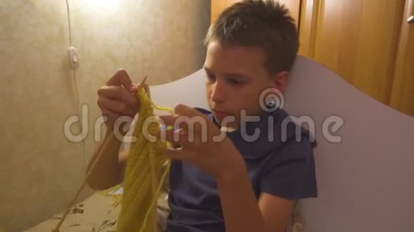 男孩正在用针织针编织围巾学习如何编织家庭作业视频的预览图