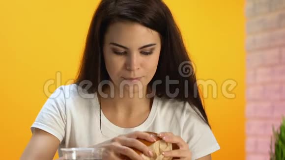 饥肠辘辘的黑发人含食欲的高脂肪汉堡不健康的快餐视频的预览图