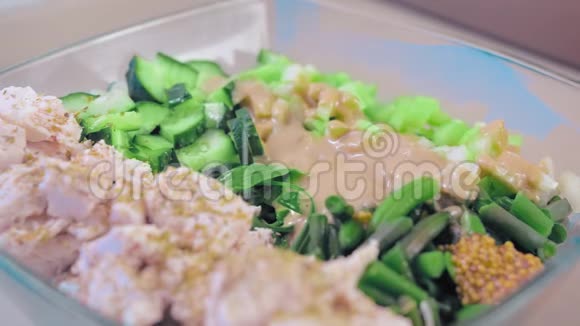 特写慢动作沙拉在一个玻璃沙拉碗鸡肉和绿色植物调味芝麻酱和法国菜视频的预览图