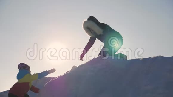 母女之间帮忙的剪影两个徒步旅行者在山顶上一个女人帮助一个女孩攀登视频的预览图