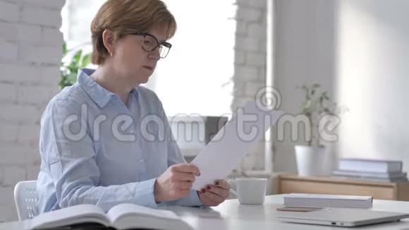 沉思的老太太在工作场所阅读文件集思广益视频的预览图