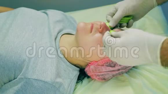 一个戴手套的男性美容师的手在女人脸上几维和黄瓜视频的预览图