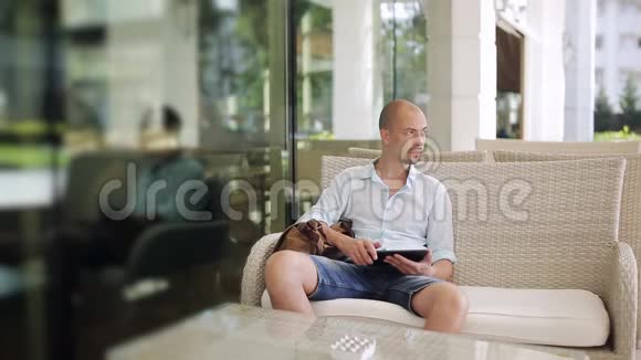 男人和女人在户外咖啡馆的露台上坐在沙发上聊天视频的预览图