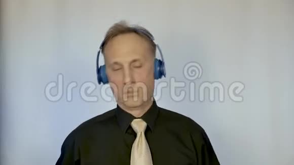 穿衬衫打领带的男人通过耳机听音乐他动作有节奏视频的预览图