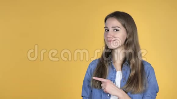 美丽的女人指着手指在侧面黄色的背景视频的预览图