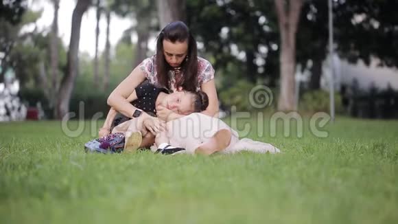 妈妈带着一个哭泣的女儿坐在草地上妈妈安慰女儿视频的预览图