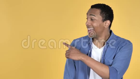 非洲青年男子侧指黄色背景视频的预览图