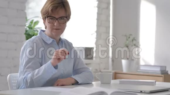 工作场所的老女人拿手指对着镜头视频的预览图