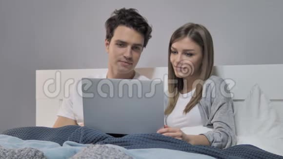 幸福的年轻夫妇在床上使用笔记本电脑视频的预览图