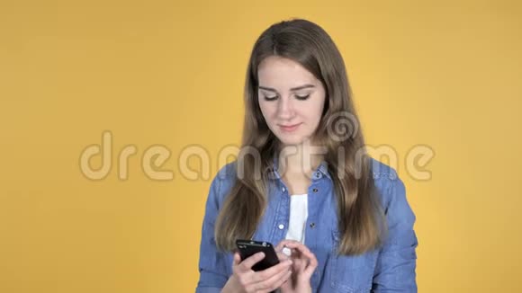 黄色背景下的美丽女性智能手机视频的预览图