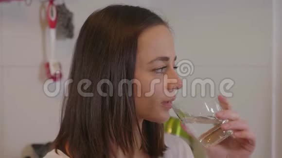 年轻女子喝一杯清澈的天然水视频的预览图