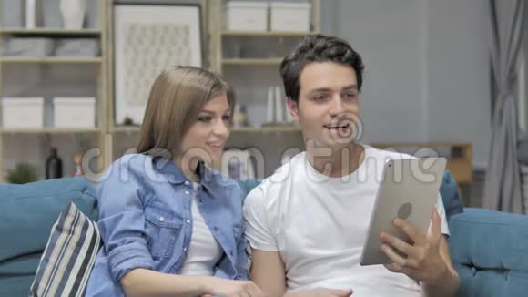 坐在沙发上的年轻夫妇在餐桌上的在线视频聊天视频的预览图