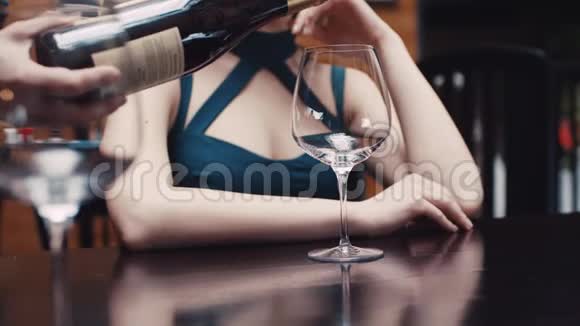 为了一个穿着诱人裙子的迷人的年轻女人她的手在杯子里倒红酒视频的预览图