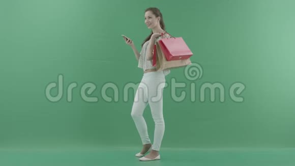 女人在智能手机上说话拿着包对着绿色屏幕视频的预览图