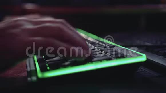 一个男人正在一个绿色背光的键盘上打字好计划美丽的灯光黑客视频的预览图