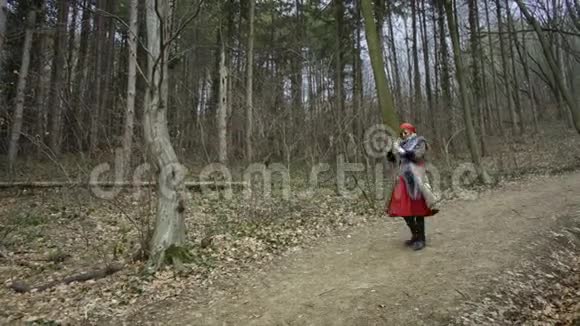 年轻漂亮的女人戴着红帽子在森林里转悠视频的预览图