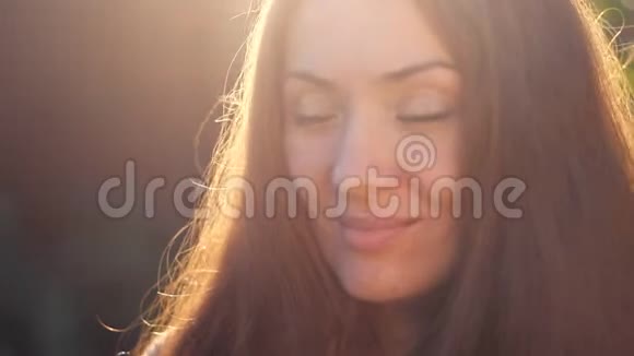 美丽的女人在夕阳的光线下微笑面部特写心情愉悦放松视频的预览图