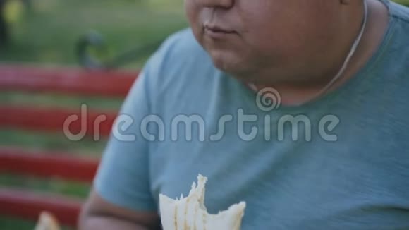 一个吃有害而美味的快餐的胖子的特写视频的预览图