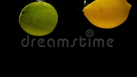 黄柠檬和青柠檬的一半在黑色背景下落入透明水视频的预览图