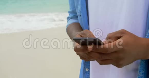 在海滩上使用手机的非裔美国人侧视4k视频的预览图