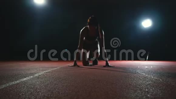 穿着黑色短裤和穿着运动鞋的t恤的运动员们在运动场馆的跑道上奔跑垫中视频的预览图