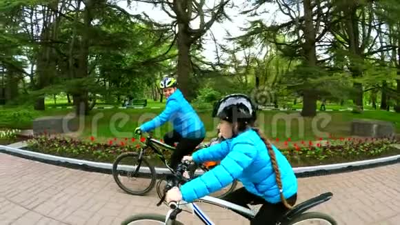 一个带着孩子的女人骑自行车在一个骑自行车的女孩旁边慢动作视频的预览图
