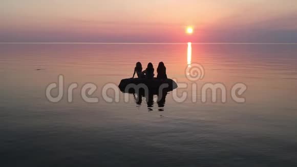 在黄昏时三个女人在海面上缓慢移动的岩石熔岩景观视频的预览图