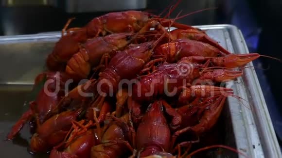 几十只红小龙虾躺在金属托盘上玉米耳朵在户外视频的预览图