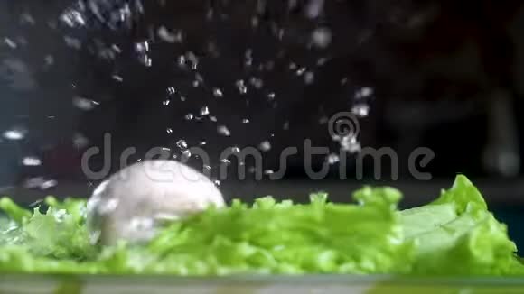 把蘑菇放在绿色沙拉上大量的水分散在不同的方向慢动作特写视频的预览图