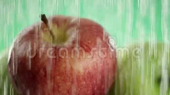 在视频中我们看到苹果水从上面落下来像雨然后像波浪特写绿色的背景视频的预览图