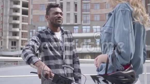 在城市建筑背景下英俊的非裔美国人站在自行车的背景下与人交谈视频的预览图