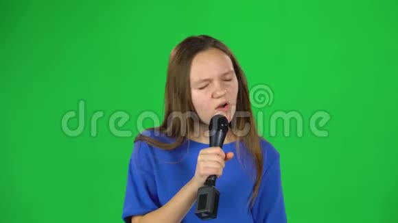 在演播室的绿色屏幕上小女孩对着麦克风唱歌视频的预览图