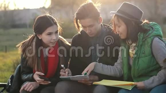 三个亚洲青少年在日落时在公园做作业视频的预览图