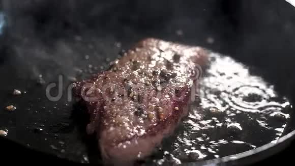 厨师用钳子把黄油涂在牛排上油融化流到热锅里胡椒牛排是油煎的视频的预览图