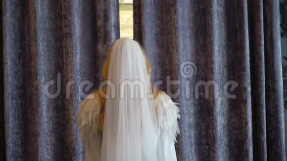 新娘穿着婚纱带着长长的挥动的面纱来到房间打开窗帘视频的预览图