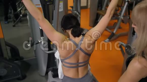 教练在健身房进行训练锻炼背部使一个美丽的黑发4K慢莫视频的预览图