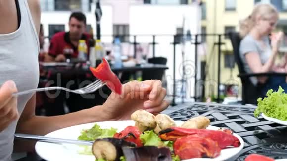 女人在客人的背景下用叉子叉着吃烤蔬菜视频的预览图