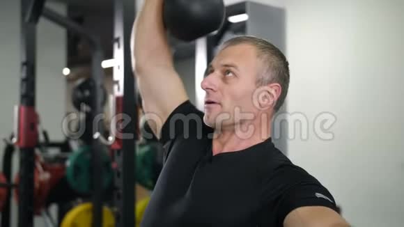 特写镜头帅哥在健身房用水壶铃做运动视频的预览图